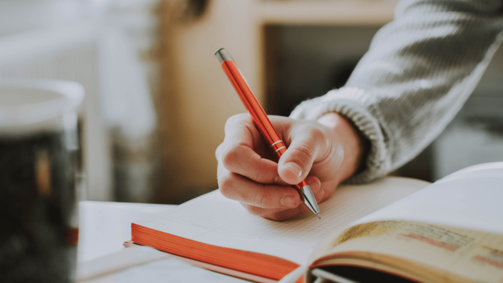 man writing notes in his journal